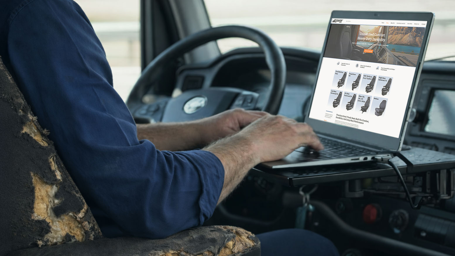 A truck driver researching replacement seating on a laptop to upgrade a damaged original seat, highlighting the convenience of buying semi-truck seats online.